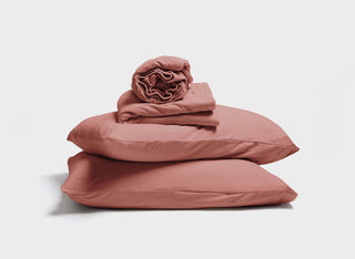 It-Fits adjustable bed sheet set in Vintage Rose, made from temperature-regulating cotton jersey. fitted sheet, flat sheet, and pillowcases are stacked