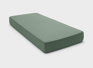 It-Fits premium knitted cotton jersey fitted sheets in sage green, perfectly fitted on a mattress with deep pockets against a neutral background.