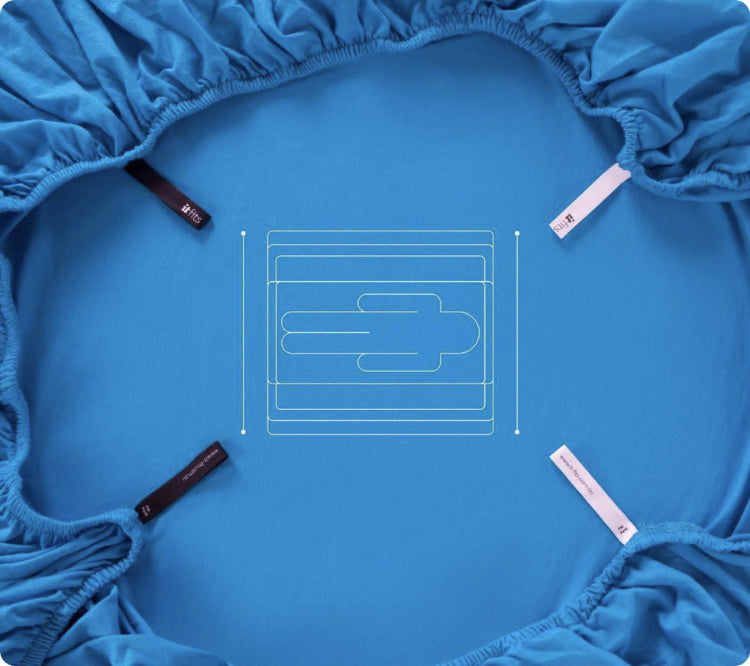 back view of the fitted sheet in royal blue crumpled and showing the magic corners and 360 elastic hem