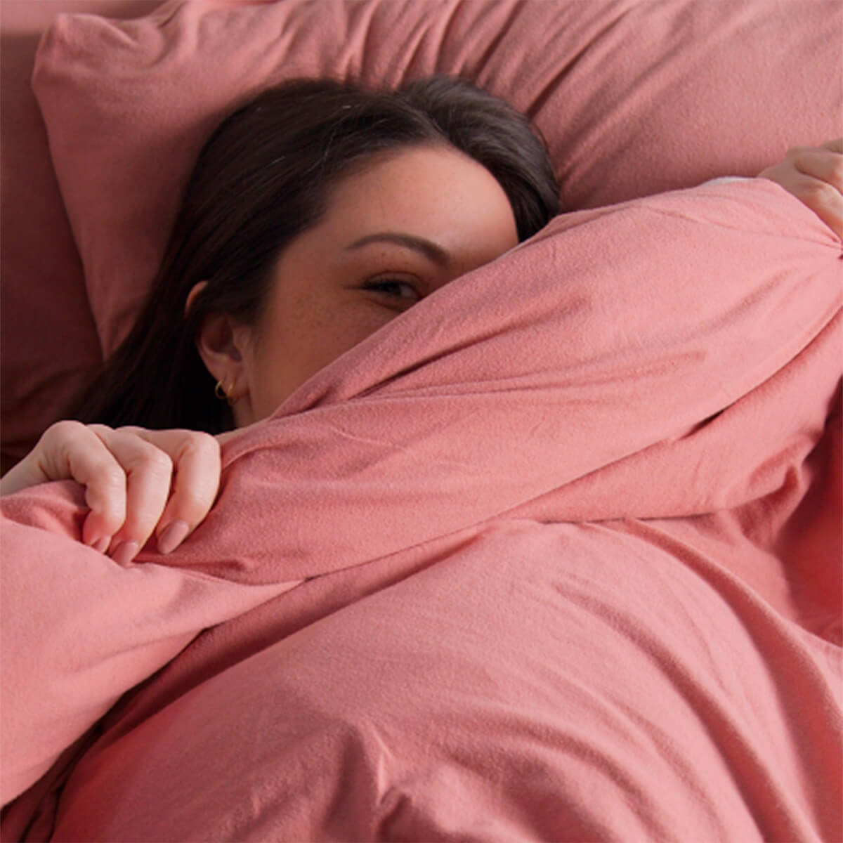 Woman relaxing in soft jersey bed sheets, designed for comfort, breathability and better sleep