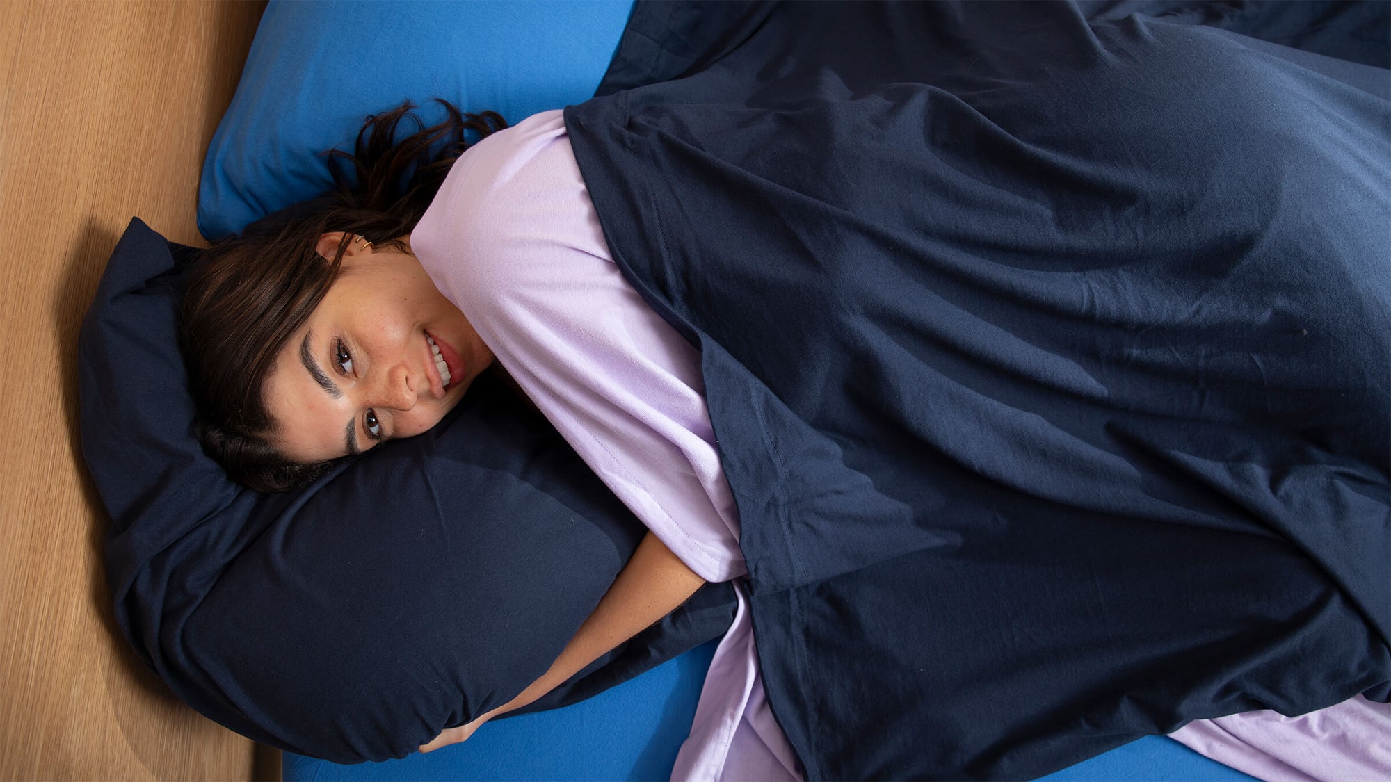 Woman relaxing comfortably in jersey bed sheets, breathable fabric designed for deep and uninterrupted sleep