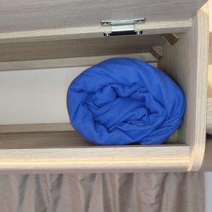 Rolled fitted sheet neatly stored in a small caravan cupboard, showing compact size for easy storage